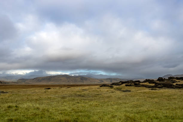 Dramatic and wild beauty of the mountains and tranquil pastures, covered with grass, moss and lichen. Cloudy sky in the autumn. Vik, Iceland.