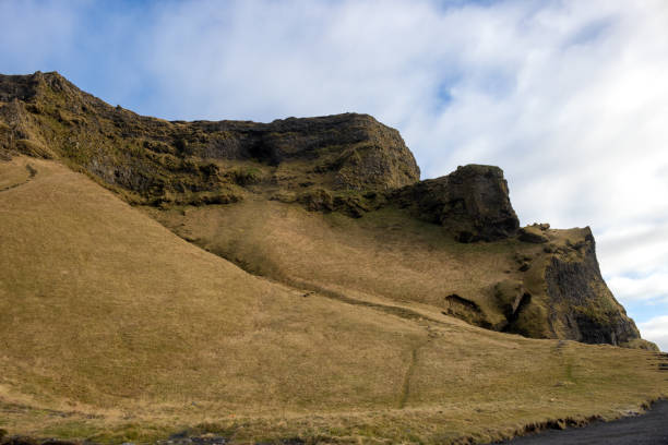 Dramatic and wild beauty of the mountains and tranquil pastures, covered with grass, moss and lichen. Cloudy sky in the autumn. Vik, Iceland.