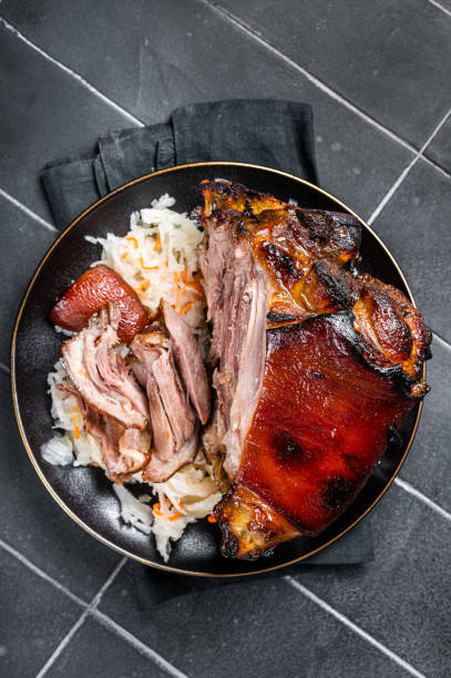 istock Roast Pork Ham Hock, knuckle with Sauerkraut on a plate. Black background. Top view 1500530610