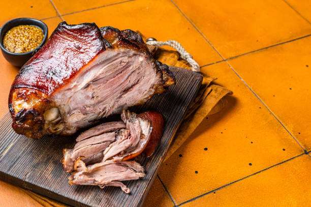istock Roasted pork Shank, knuckle on a wooden board. Orange background. Top view. Copy space 1500530737