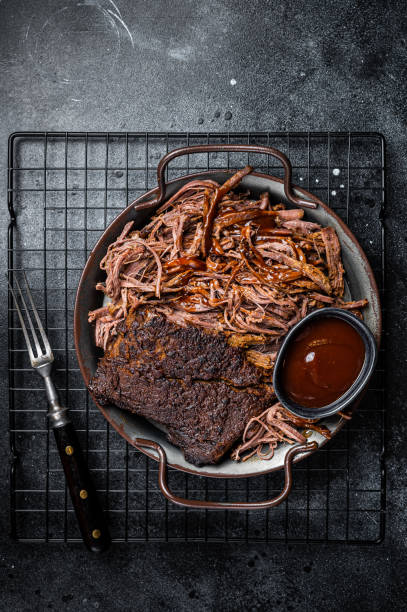 istock Slow Cooked Pulled Beef, Traditional meat rubbed with spices and smoked in a Texas smoker. Black background. Top view 1500530913