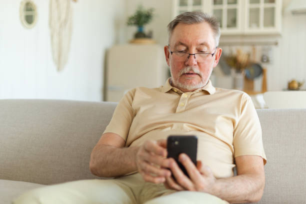 istock Happy middle aged senior man holding using smartphone touch screen typing scroll page. Stylish older mature beard grandfather with cell phone using internet social media apps at home. Shopping online. 1500532419