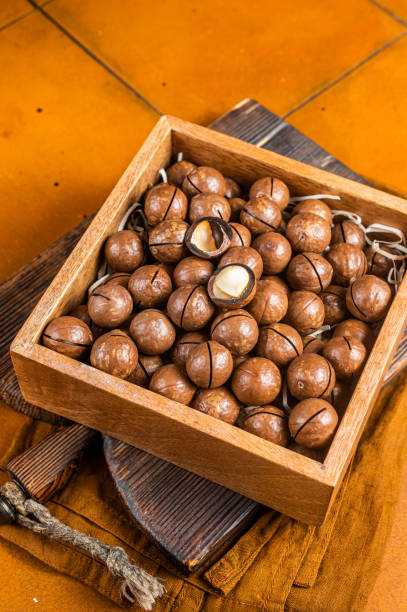 istock Macadamia natural nuts in a box. Orange background. Top view 1500533144