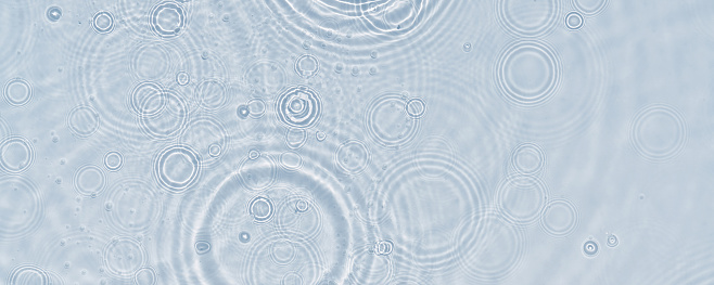 A top vie closeup of multiple waterdrops on a light blue background