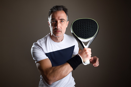 Padel player portrait detail equipped with sportswear and isolated dark background. Front view.