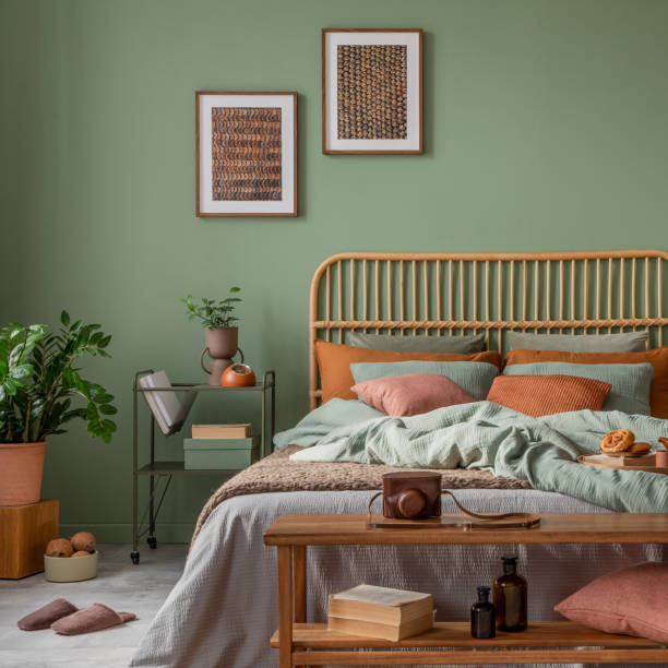 istock Stylish bedroom interior design with mock up poster frame, bamboo bed, night table, plants, folding screen and creative home accessories. Eucalyptus wall. Template. Copy space. 1500540007