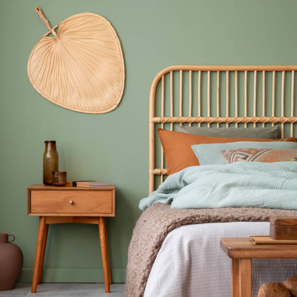 istock Elegant bedroom interior design with bamboo bed, modern bedclothes, night table and stylish accessories. Eucalyptus wall. Template. Copy space. 1500540028