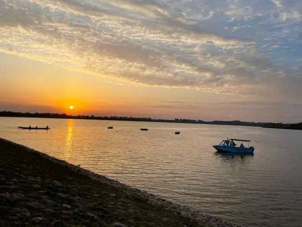 Stock photo showing sunset viewed from bank of Sukhna Lake, Chandigarh, India. Boating on the popular reservoir is a popular tourism activity on this migratory bird sanctuary that the Government of India have declared a protected national wetland.