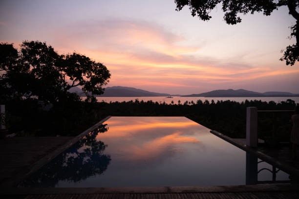 Intense orange and pink sunset above the water in Puerto Princesa, Palawan, Philippines. Sun going down, burning sky, golden hour. Sunset reflecting in infinity pool. Scenic view.