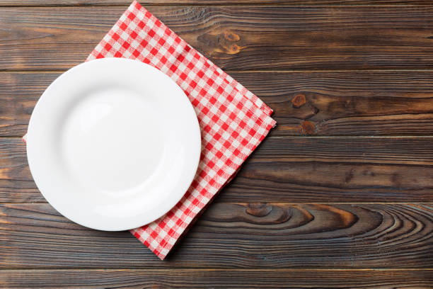istock Top view on colored background empty round white plate on tablecloth for food. Empty dish on napkin with space for your design 1500560540