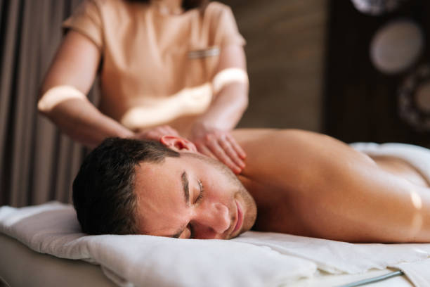 istock Closeup face of relaxed young man getting back massage in spa salon lying on massage table closed eyes. Happy male lying on stomach having full body treatment 1500562907