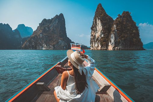 Mujer asiática viajera relajarse y viajar en barco tailandés de cola larga en la presa de Ratchaprapha en el Parque Nacional Khao Sok Surat Thani Tailandia photo