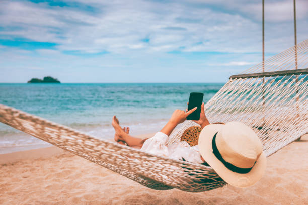 mulher asiática viajante com celular relaxa em rede na praia de verão tailândia - summer women hammock nature - fotografias e filmes do acervo