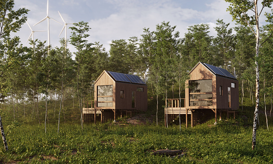 Energy efficient cabins with solar panels and wind turbines behind it, day scene. (3d render)