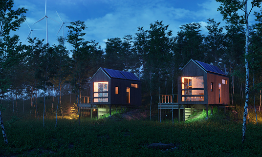 Energy efficient cabins with solar panels and wind turbines behind it, evening scene. (3d render)