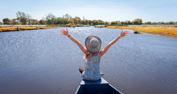 Briere Marshland- Happy woman tourist in wooden boat in marsh- France- natural regional park of Briere- Pays de la Loire