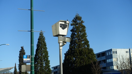 A speed camera mounted on an urban roadside, angled to capture the speed of passing vehicles