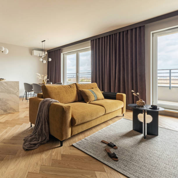 istock Creative and modern vintage open space interior design with yellow sofa and turquoise kitchen with a marble island. Grey carpet on the herringbone parquet with coffee table, brown curtain in windows. Template. 1500566102