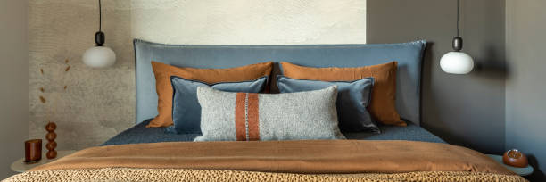 istock Stylish composition of modern bedroom interior. Bed, creative lamp and elegant personal accessories. Concrete wall. Brown sheeets. Minimalistic masculine concept. Template. 1500566345