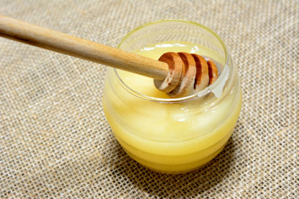 istock fresh light honey in drinking glass with wooden deeper, close up 1500569695