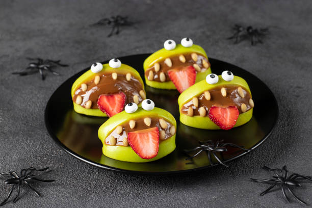 Spooky green apple monsters for Halloween party on dark gray background decorated with spiders stock photo