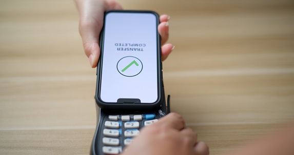 Close-up of Hand of customer paying with contactless mobile banking with NFC technology. Client makes transaction pay the bill on cashier machine in restaurant store. Payment and technology concepts.