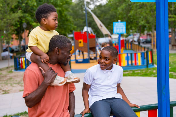 African black ethnicity father talking with his children in the playground of the city park