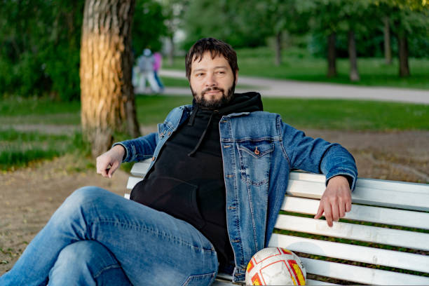 istock attractive caucasuan bearded young man sitting on bench in park looking aside 1500575251
