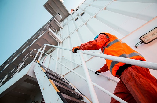 A construction worker wearing an orange vest is climbing a staircase
