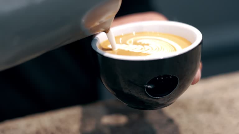 Closeup of latte, art and milk foam in cup, coffee and barista with drink making process and cappuccino in cafe. Small business owner, person prepare espresso with caffeine, creativity and service