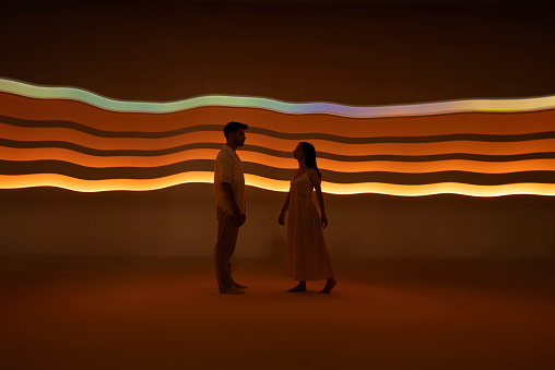 Woman and man standing in front of orange light trails.