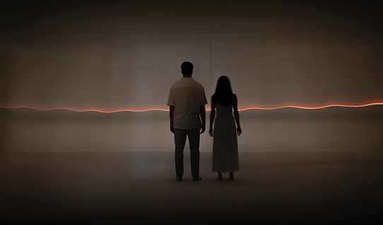 Woman and man standing in front of orange light trails.