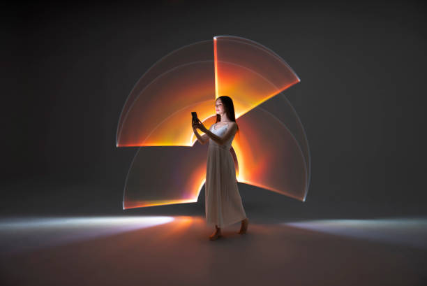 Young woman using a smart phone Young woman using a smart phone in front of orange light trails. mobile phone lights up stock pictures, royalty-free photos & images
