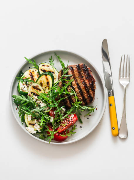 istock Steak and  vegetable salad with grilled zucchini, tomatoes and arugula on a light background, top view 1500584923