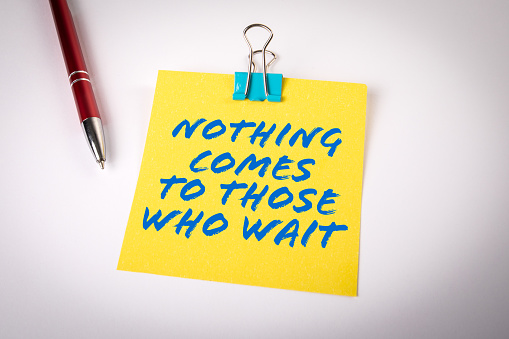 Nothing Comes to Those Who Wait. Yellow sticky note with text on a white background.