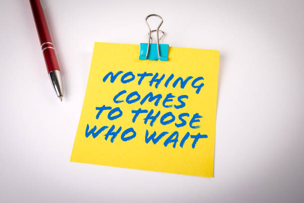 Nothing Comes to Those Who Wait. Yellow sticky note with text on a white background stock photo