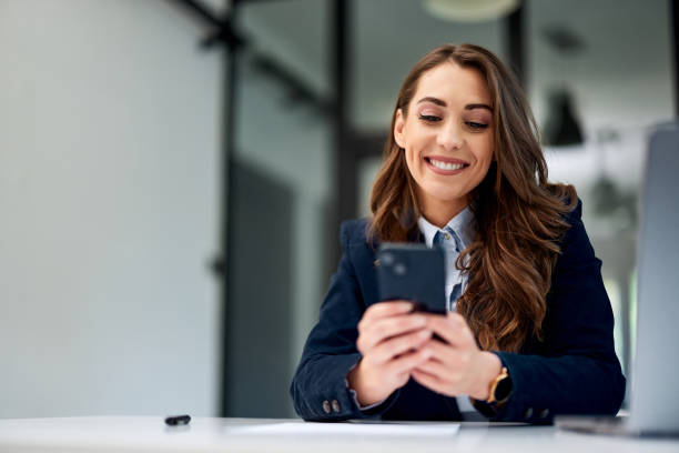 istock A smiling businesswoman using a mobile phone at the workplace, elegantly dressed. 1500601163