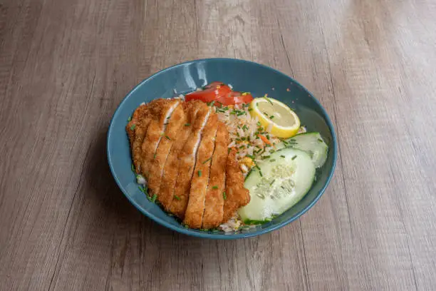 Photo of Paris, France - 06 20 2023: Asian dishe culinary Still Life. Chicken Cantonese rice with tomatoes, cucumbers and lemon