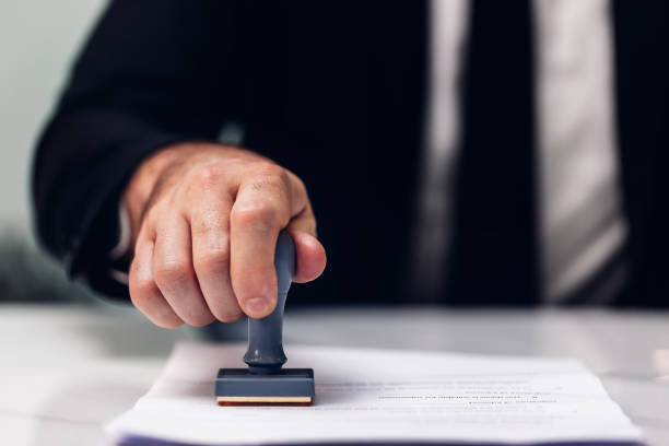 istock Business Man Stamping With Approved Stamp On Document. Business approve Stamp and certificate concept. Businessman Hands Stamping a document 1500604680