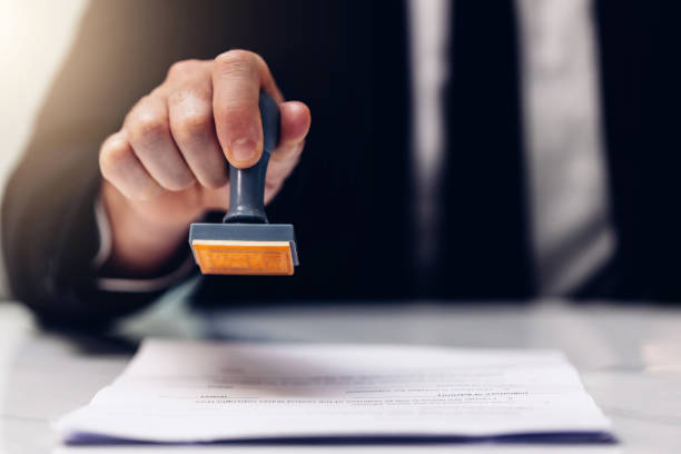 istock Business Man Stamping With Approved Stamp On Document. Business approve Stamp and certificate concept. Businessman Hands Stamping a document 1500604703
