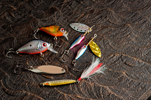 Set of metal and plastic lures for fishing on dark oak, copy space