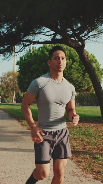 Young man running along the path in the park