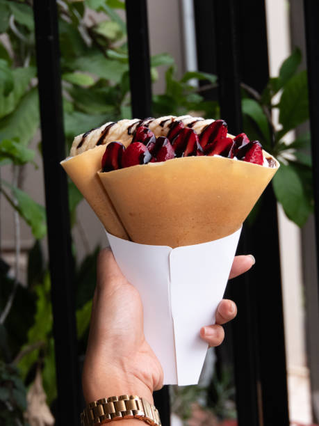 Crispy crepe filled with luscious strawberry whipped cream is a delightful treat that combines the satisfying crunch of the crepe with the light and creamy sweetness of the strawberry filling.close up