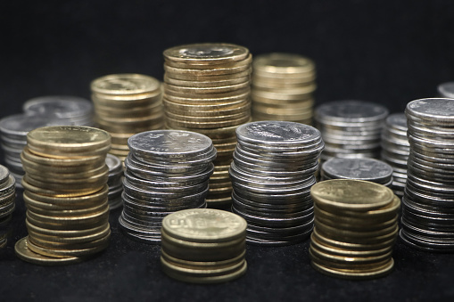 closeup shot of rows of gold and silver coins arranged and stacked in towers of different size isolated in a black background