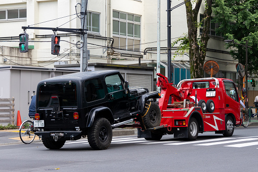 Tokyo, Japan - May 30 , 2023 :  A tow truck moving a car on a street in Tokyo, Japan.