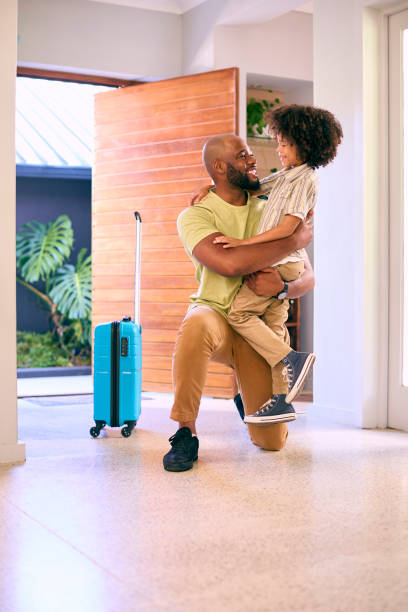 istock Son Greeting Father Returning Home With Luggage From Trip Away 1500619753