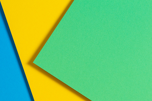 Abstract color papers geometry flat lay composition background with blue, yellow and green color tones.