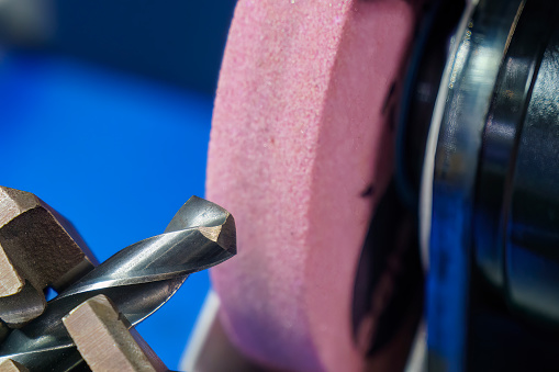 Observe de cerca el proceso de rectificado de herramientas de perforación con rueda de piedra abrasiva. photo