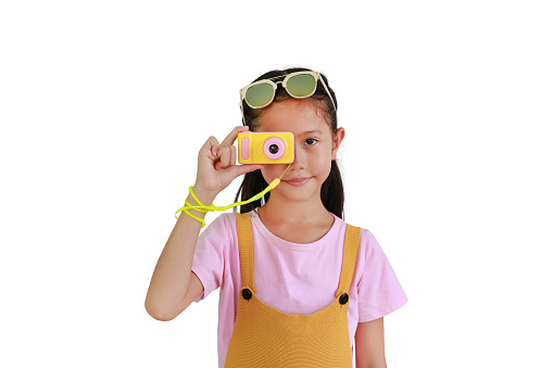 Asian little girl child taking picture with photo camera isolated on white background.