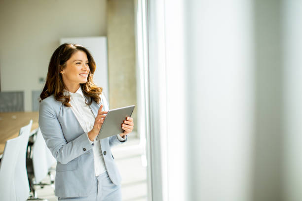 istock Young woman working on digital tablet by the office window 1500623379